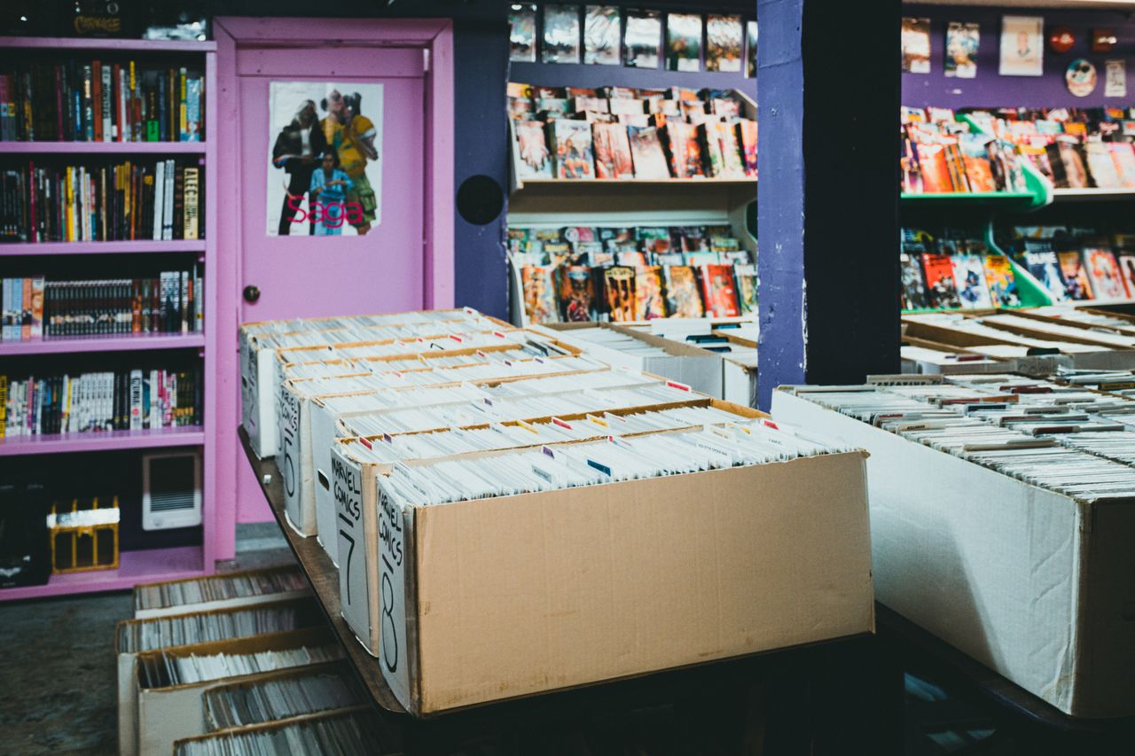 services-02 A colorful comic book store with organized shelves and boxes of comics for sale.